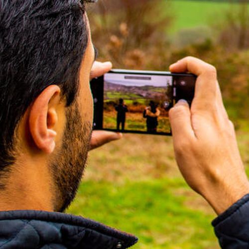 A group of friends taking photos of the English countryside from Fire Beacon Hill local nature reserve in Devon, UK