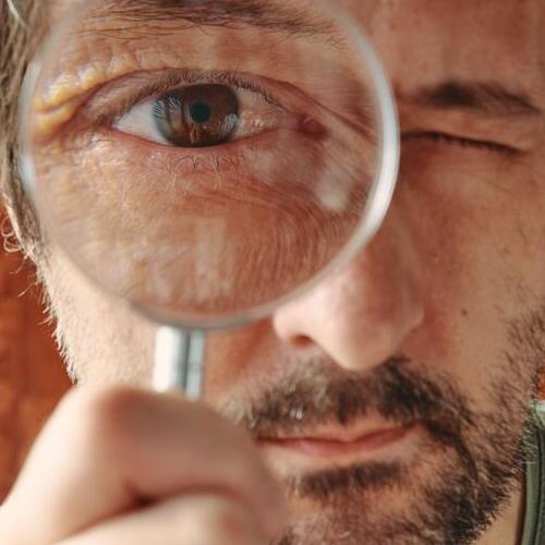 Curious man looking through magnifying glass with intense desire to know and understand